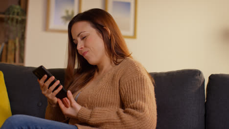 Mujer-Sentada-En-Un-Sofá-En-Casa-Viendo-Una-Película-O-Programa-O-Navegando-Por-Internet-En-Un-Teléfono-Móvil-6